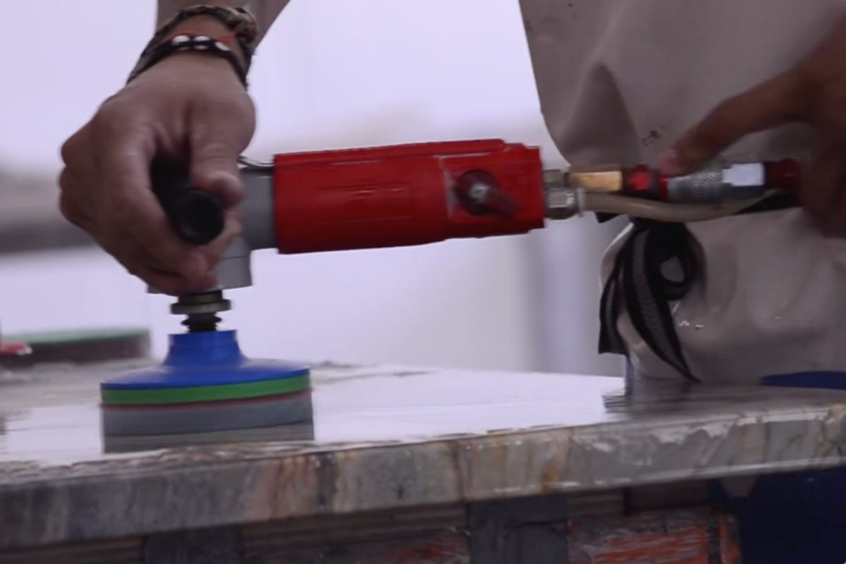A fabricator hand-polishing the finished edge of a slab with a wet polisher