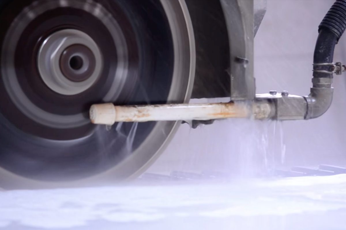 CNC bridge saw cutting a porcelain slab under water spray on the Commerce City fabrication floor